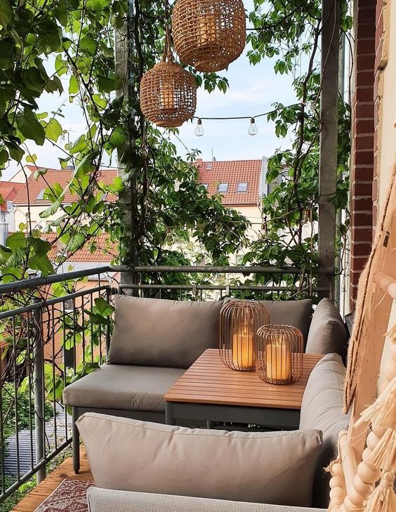 A chic modern balcony with modern furniture, green plants and hanging lamps, candle lanterns and vines climbing up the entire room