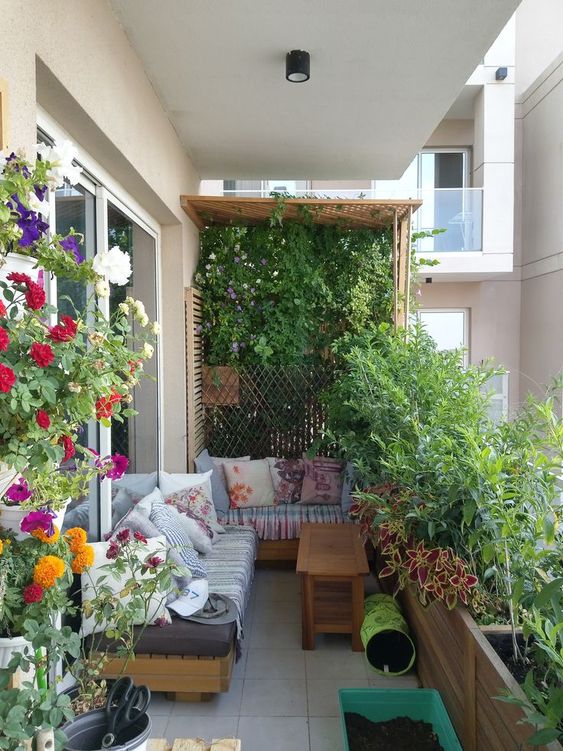 A garden-style balcony with a trellis and greenery, potted plants and flowers, a corner sofa and cushions is fantastic