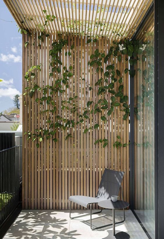 A minimalist balcony with a chair, a side table and a trellis and climbing plants is a cool spot if you love minimalist decor