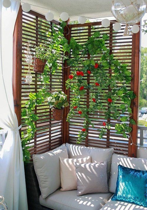 A modern balcony with a sofa with cushions, a trellis with vines and flowers and attached planters is a cool solution