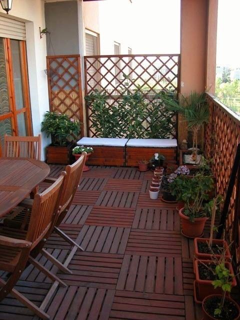 a modern, rustic patio with stained floors and furniture, potted plants, a trellis of vines and a bench next to it