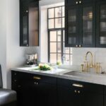 Black kitchen features glass reeded upper cabinets and black lower .