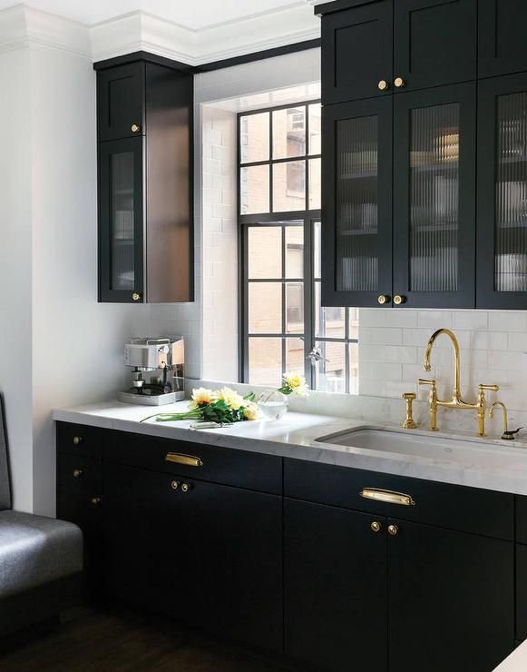 Black kitchen features glass reeded upper cabinets and black lower .