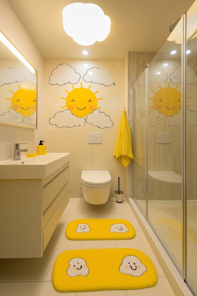 A cheerful bathroom with sun and cloud decor, yellow mats and modern fixtures.