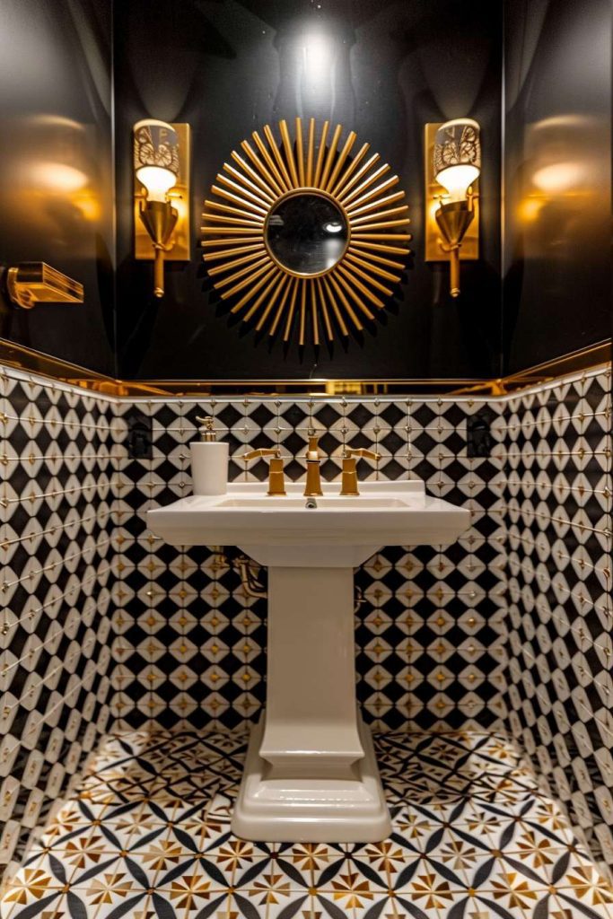 Black and gold style bathroom with pedestal sink, geometric patterned tiles and a sunburst mirror flanked by two sconces.