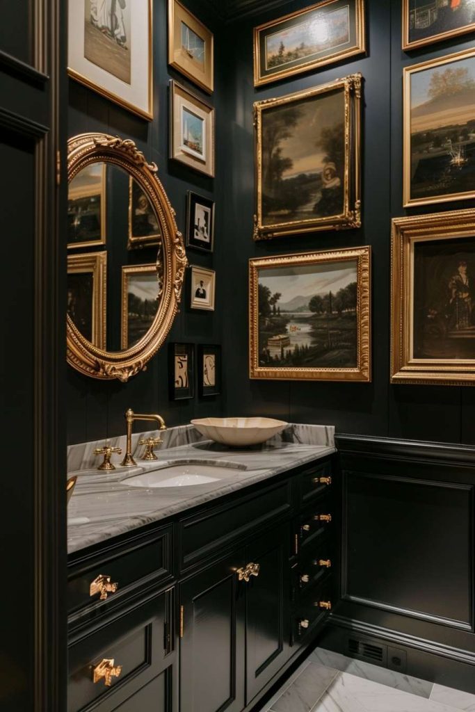 A luxurious bathroom with dark walls, plenty of framed artwork, a large round mirror, gold fixtures and a marble sink.