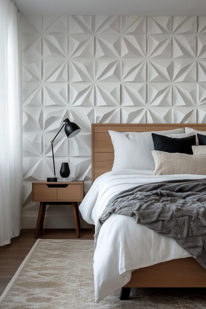 Modern bedroom with geometric patterned wall, wooden bed frame and white bed linen. A black lamp and decor sit on a side table. A gray blanket is draped over the bed.