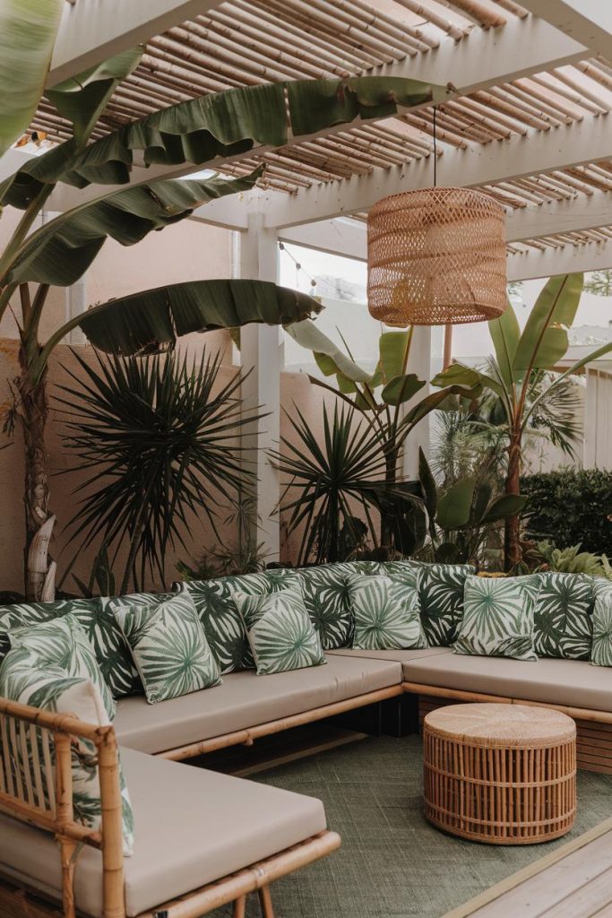 Outdoor seating area with a bamboo-style couch, green leaf-patterned cushions, a wicker table and <a href=