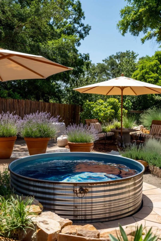 A round metal water storage tank flanked by lavender pots and shaded by parasols in a sunny backyard.