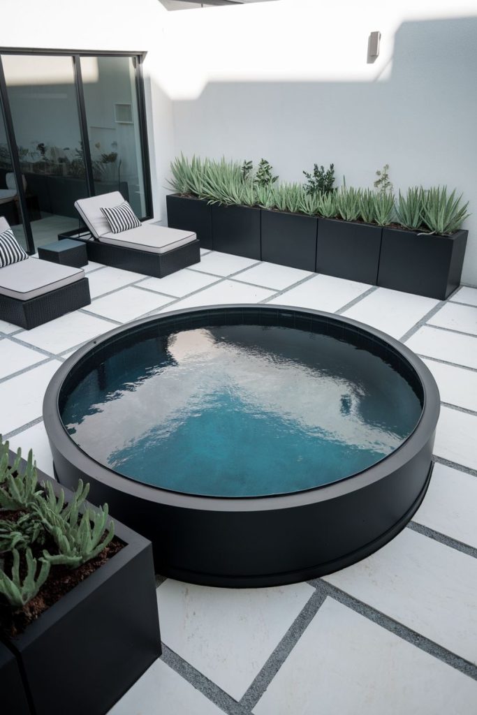 Modern patio with black storage pool, striped loungers and planters.