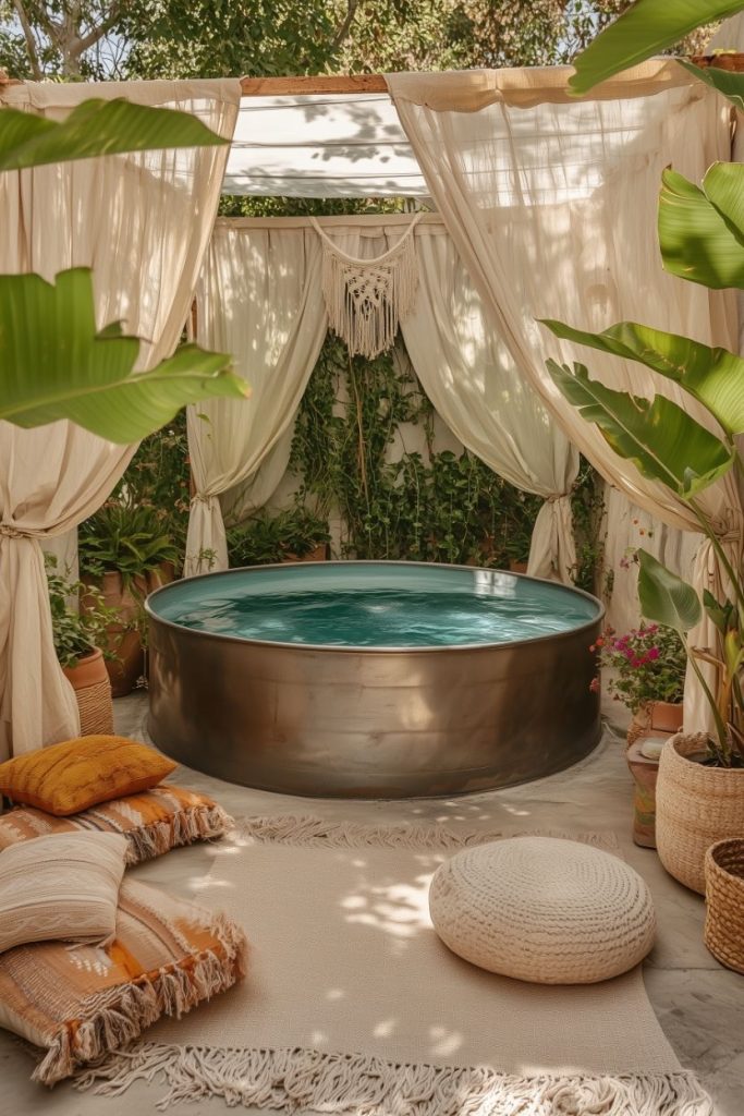 A cozy stock tank pool surrounded by curtains and lush greenery with cushions and rugs on the floor.