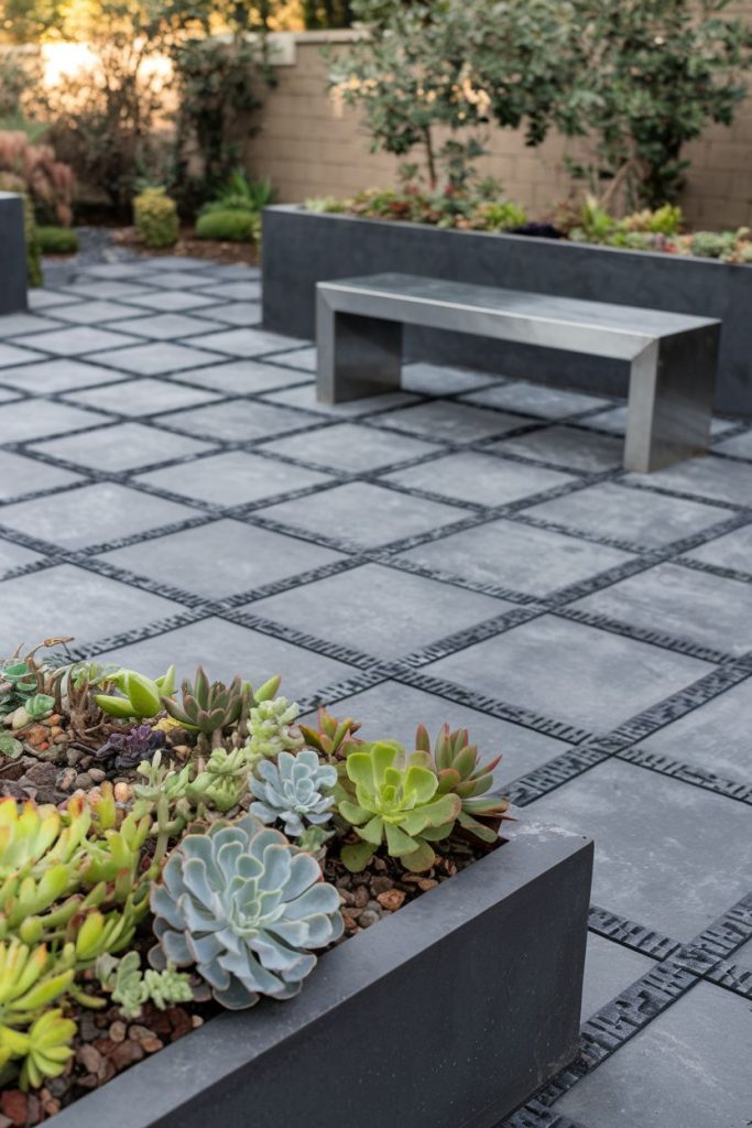 Modern patio with tile grid design, rectangular planters full of succulents and a minimalist metal bench.