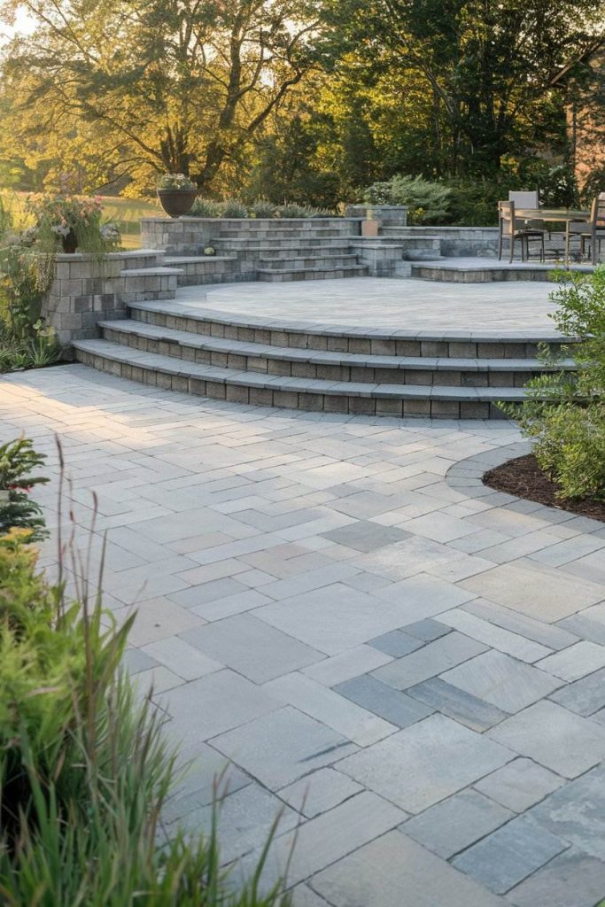 Stone terrace with several steps surrounded by greenery and garden furniture.