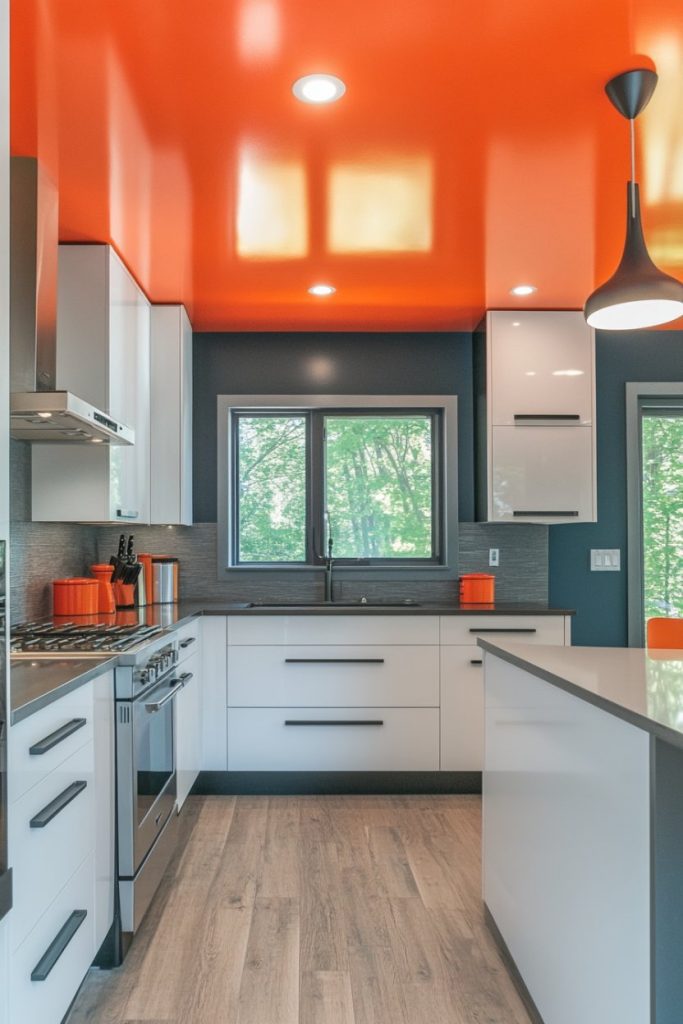 Modern kitchen with white cabinets, stainless steel appliances and an orange ceiling. Large window provides natural light. Gray walls and wooden floors create contrast.