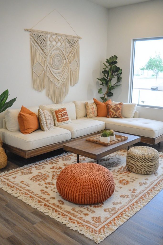 A cozy living room features a white sofa set with orange cushions, a wooden coffee table, a macrame wall hanging and a patterned rug. Plants add a touch of green.