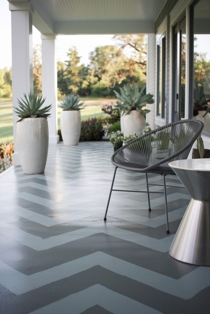 A porch with a zigzag patterned floor, a metal chair, a small table and large potted plants against a green background.