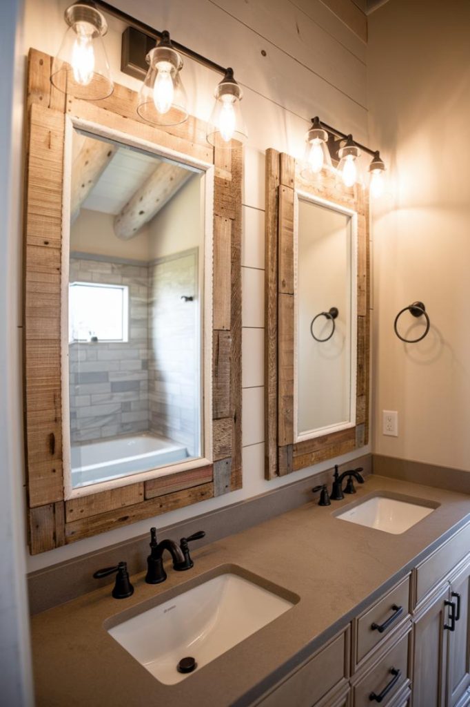 Bathroom with two sinks, wooden-framed mirrors, black taps and wall lights. Shower area visible in the mirror image.