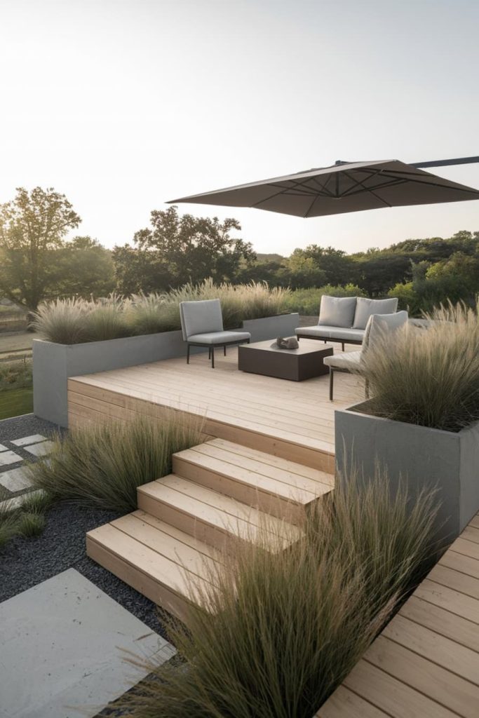 Modern outdoor terrace with wooden decking, seating area, parasol and decorative grasses overlooking a picturesque landscape.