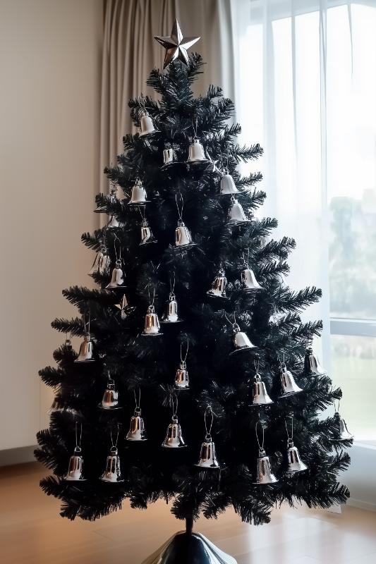 Artificial Christmas tree decorated with numerous silver bell ornaments placed next to a window with light curtains.