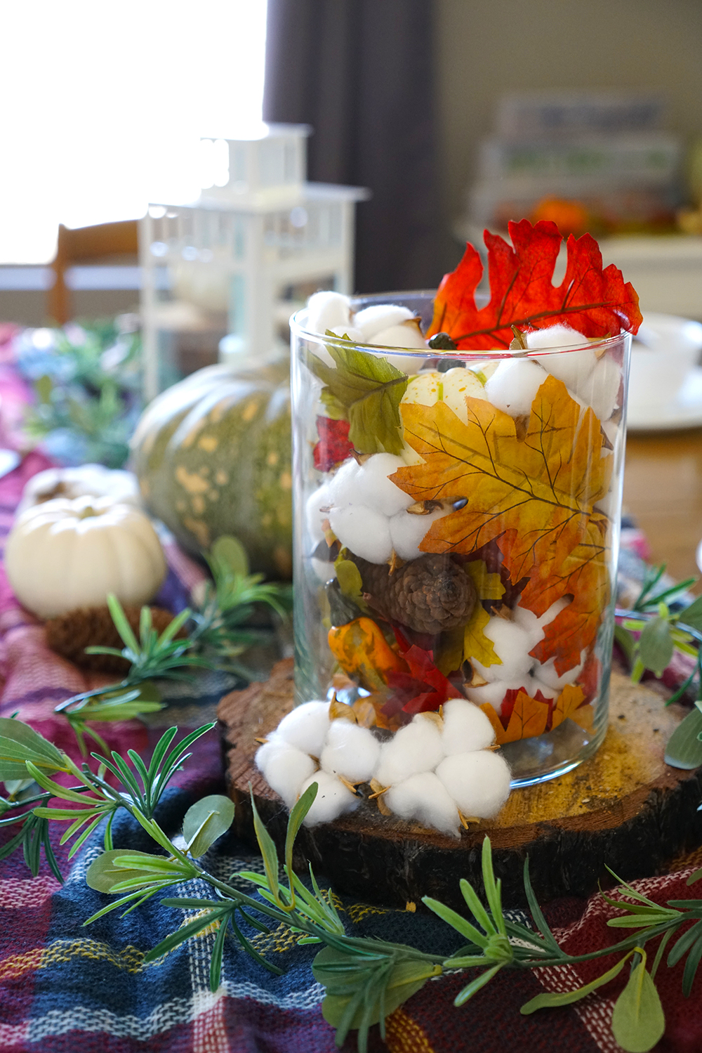 Fall tablescape with plaid blanket, pumpkins and cotton stalks