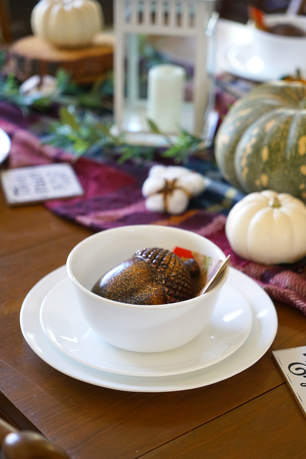 White Corelle dinnerware set with glittery acorn, wooden table and checkered blanket.