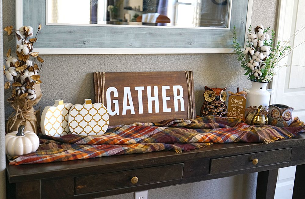 Wooden table with checkered autumn blanket, cotton stalks and white pumpkins