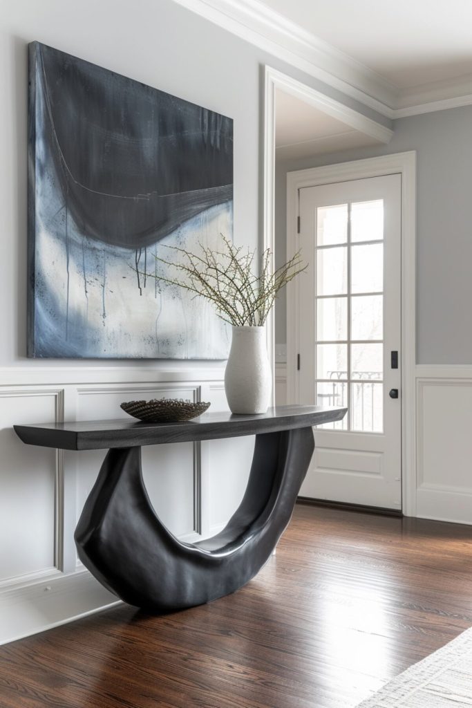 a black console table with a bowl and a white vase with dried plants and a large modern abstract painting on the wall