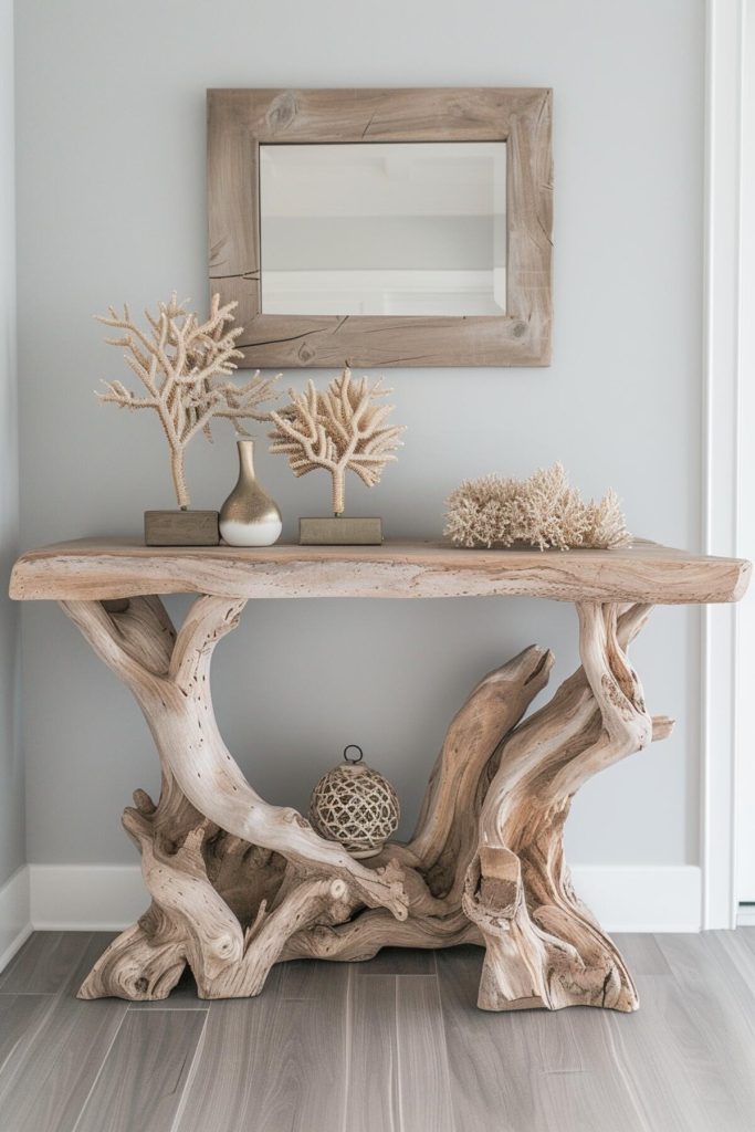 a driftwood console table with a driftwood ball and corals and a light wood framed mirror hanging above