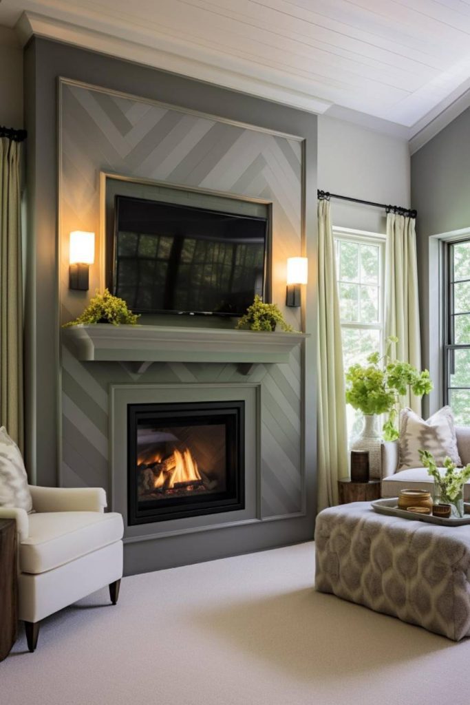 A cozy living room features a lit fireplace beneath a wall-mounted television, flanked by two sconces and decorated with green plants. White armchairs and a patterned ottoman complete the seating area.