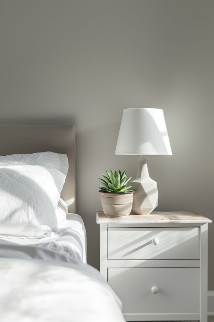 minimalist white bedside table with a succulent plant in a pot and a geometric white lamp