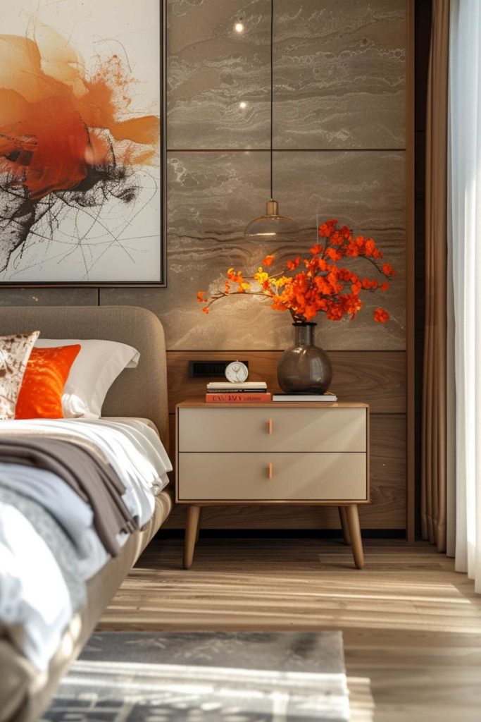 A Nordic-style bedside table with a large vase of artificial orange blossoms, a small clock and a stack of books, and a glass pendant lamp above 