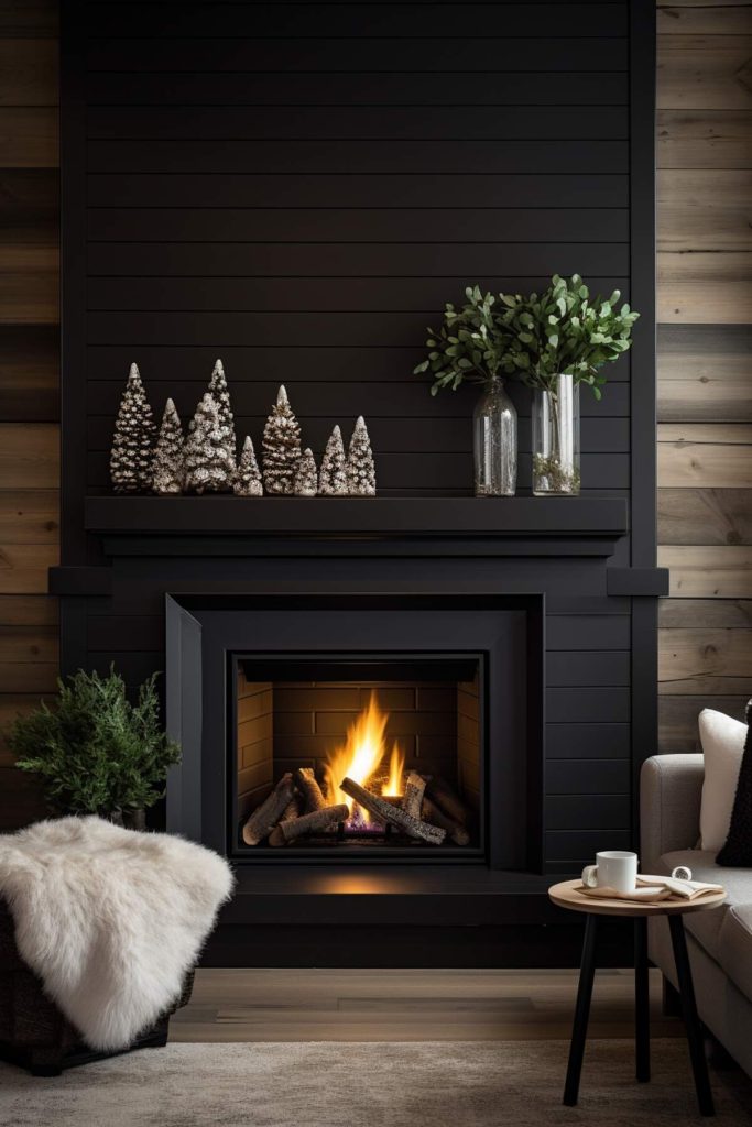 A living area with a black fireplace and mantel is decorated with green eucalyptus trees in glass vases and artificial Christmas trees