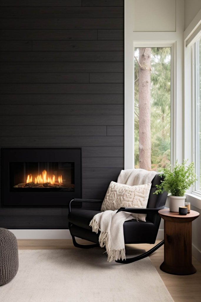 a living area with a floor-to-ceiling black fireplace and a black rocking chair with a cozy throw blanket next to it