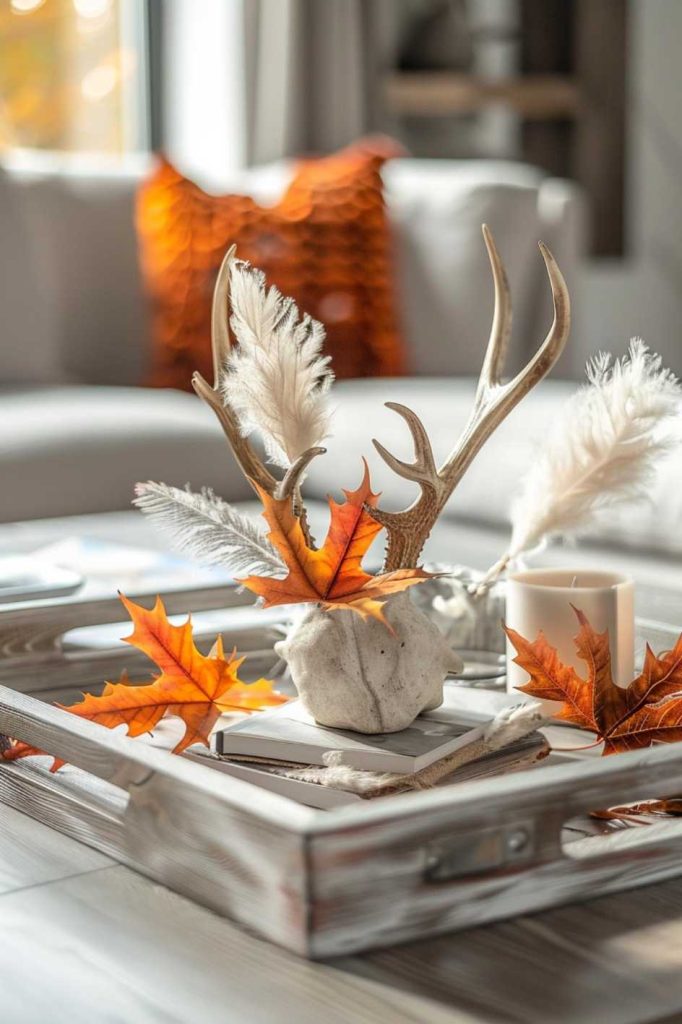 A collection of feathers, a deer antler, bright autumn leaves and books arranged on a <a href=