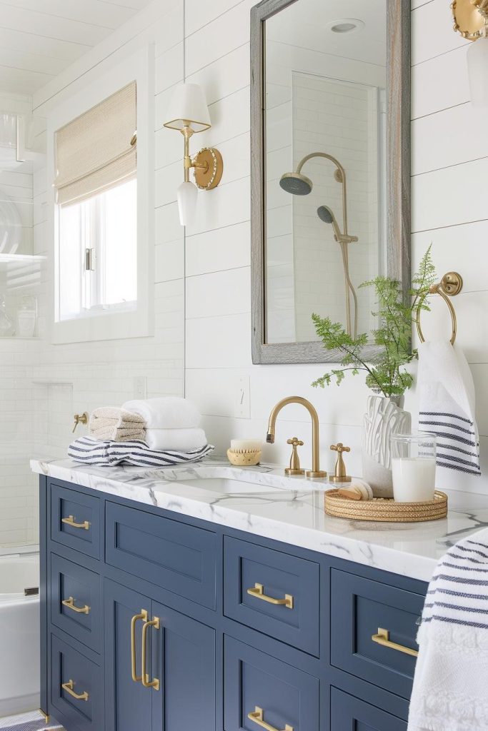 Navy vanities paired with brass fixtures give this bathroom a nautical touch, while white and navy striped towels add a playful nod to seaside style.