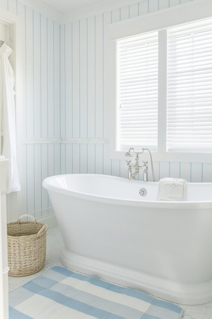 Subtle white and blue striped wallpaper creates a gentle, nautical striped pattern without overpowering the coastal bathroom aesthetic. If the statement wallpaper gets most of the attention, you can keep the rest of the decorations minimal.