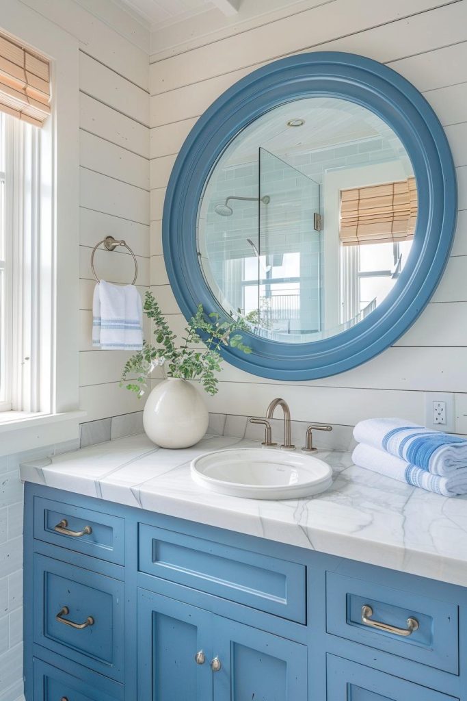 A large, round mirror with a rich blue frame is reminiscent of a porthole and reflects the charm of the coast.