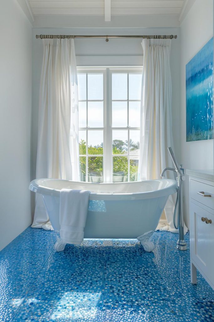 Indulge in nautical charm as a mesmerizing mosaic of blue tiles adorns the floor, providing a tactile experience that exudes a distinctly nautical feel with every step, adding an elegant touch of coastal charm to the bathroom.