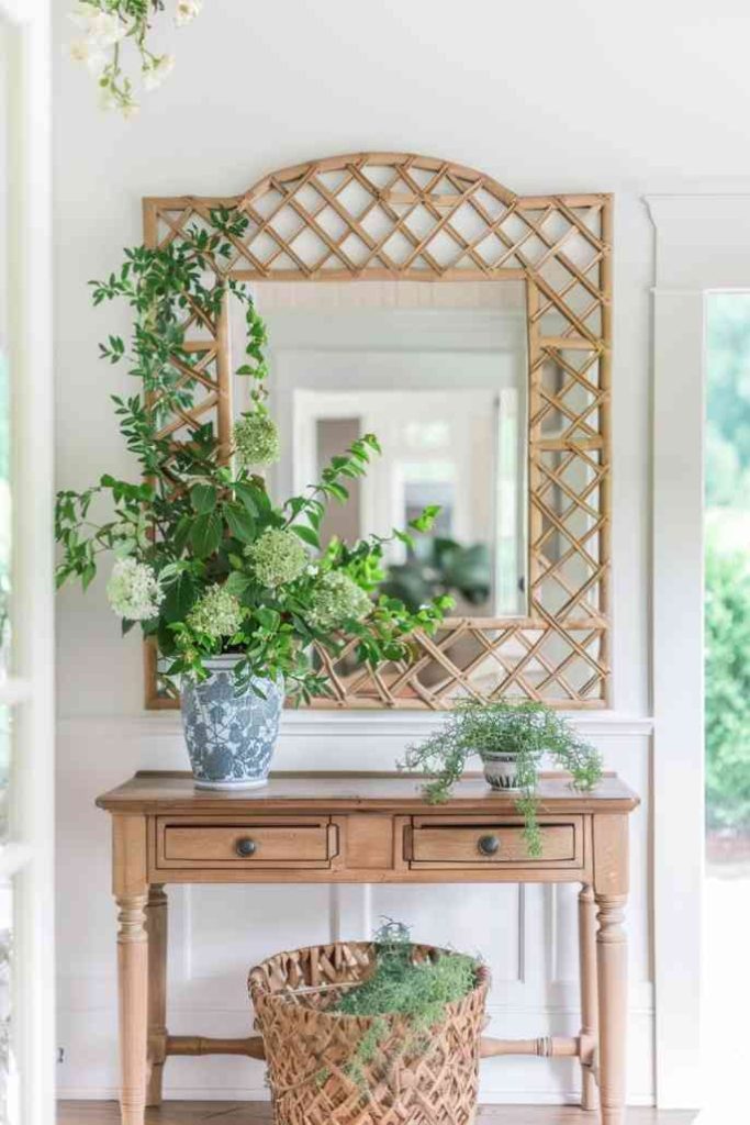 Create a captivating tableau in the farmhouse entryway, where a trellis-framed mirror sits above an entryway table adorned with lush greenery. 