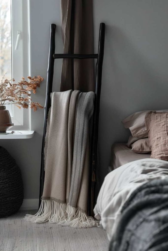 A cozy bedroom scene with a ladder with a ceiling, a bed with beige bed linen and a small window linen with dried plants in a vase.