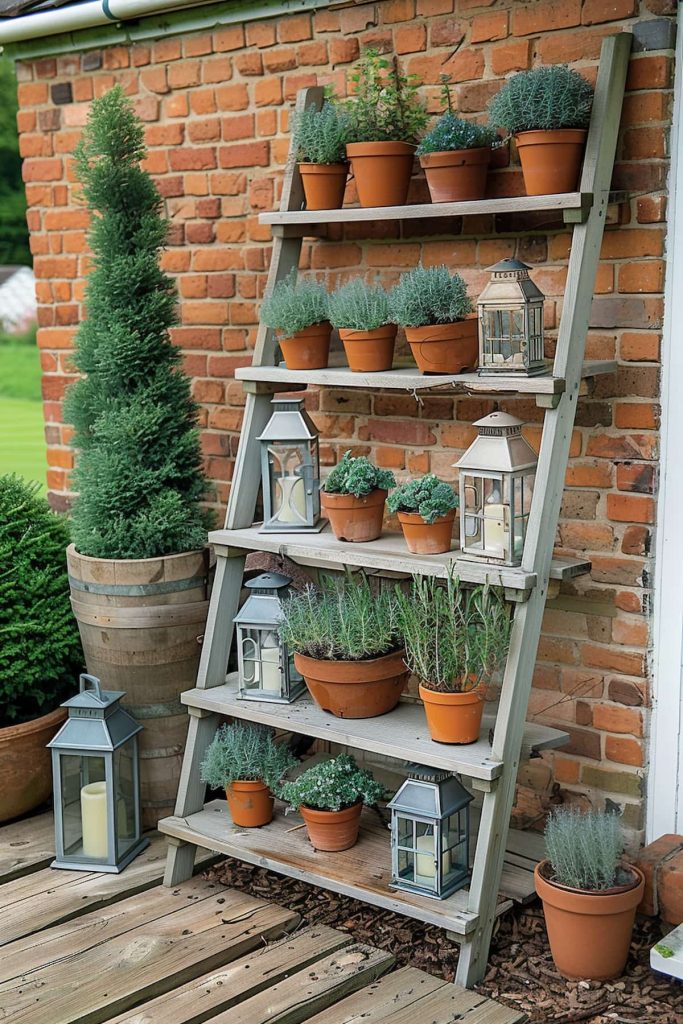 A wooden conductor shelf against a brick wall contains several terracotta pots with different herbal plants. Several metal lanterns are interspersed between the pots. On the left is an evergreen starting smoke on the wooden deck.